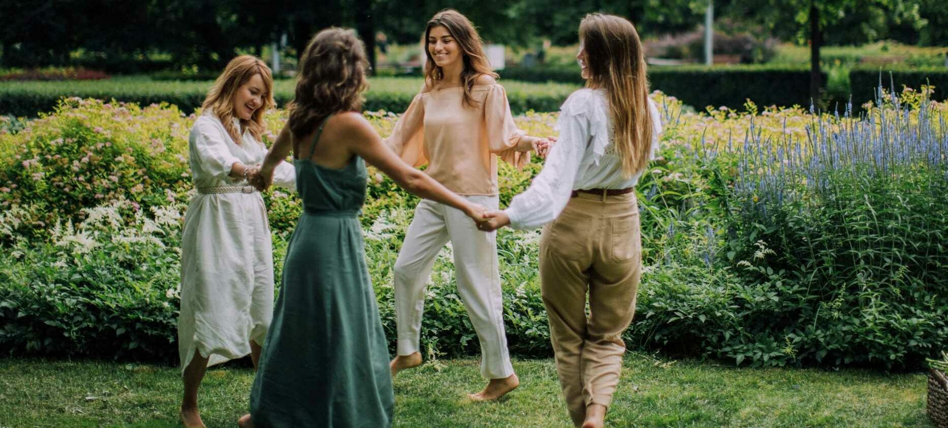 4 femmes qui se tiennent les mains en cercle dans un parc
