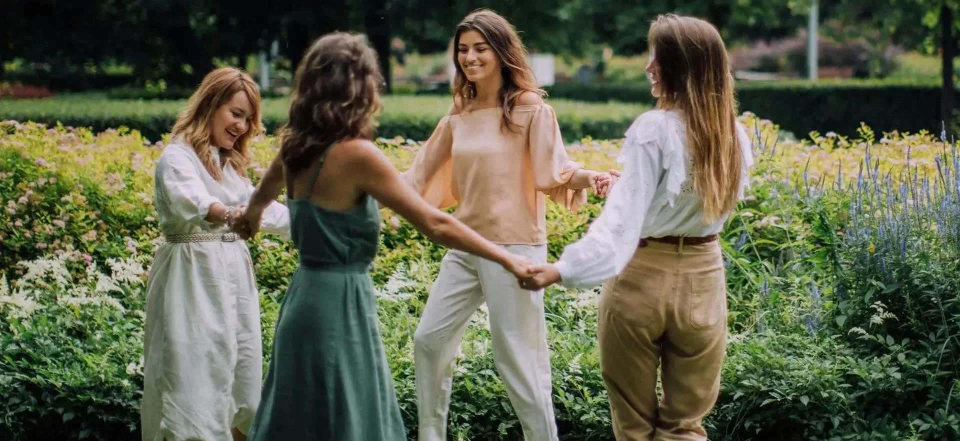 4 femmes qui se tiennent les mains en cercle dans un parc